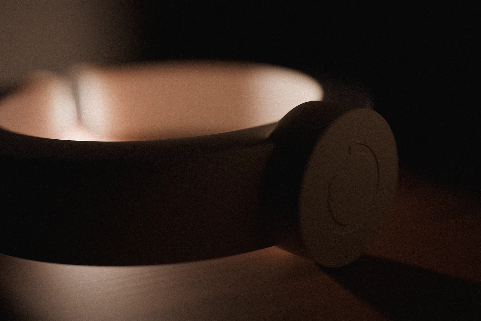 The base of the NOCT lamp, lying on its side on a bedside table, the ring mark debossed into the ceramic foot.